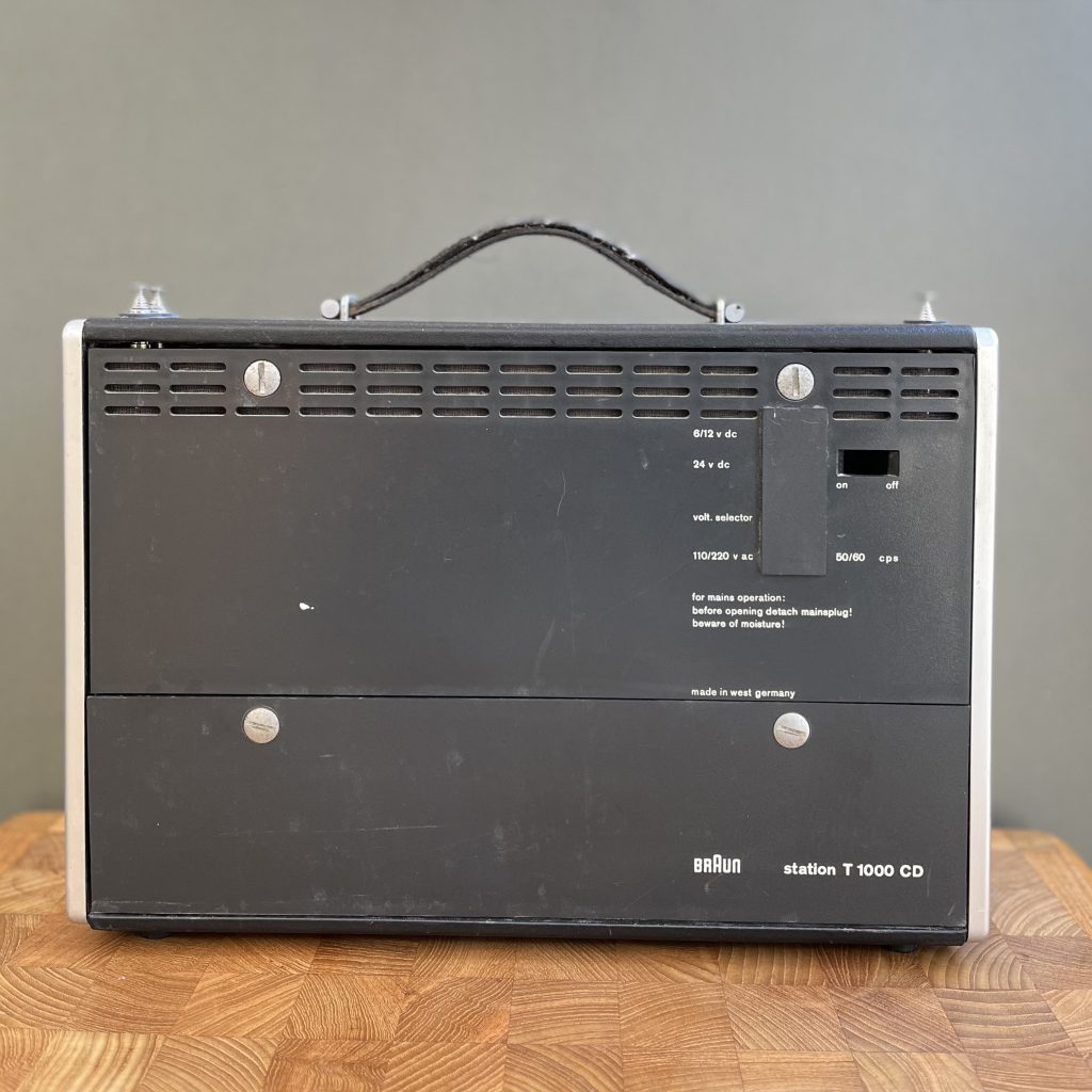 Rear view shows the voltage selector text for the TN1000 adapter when fitted on the top right. On the lower half are the two coin slot fasteners for battery access.