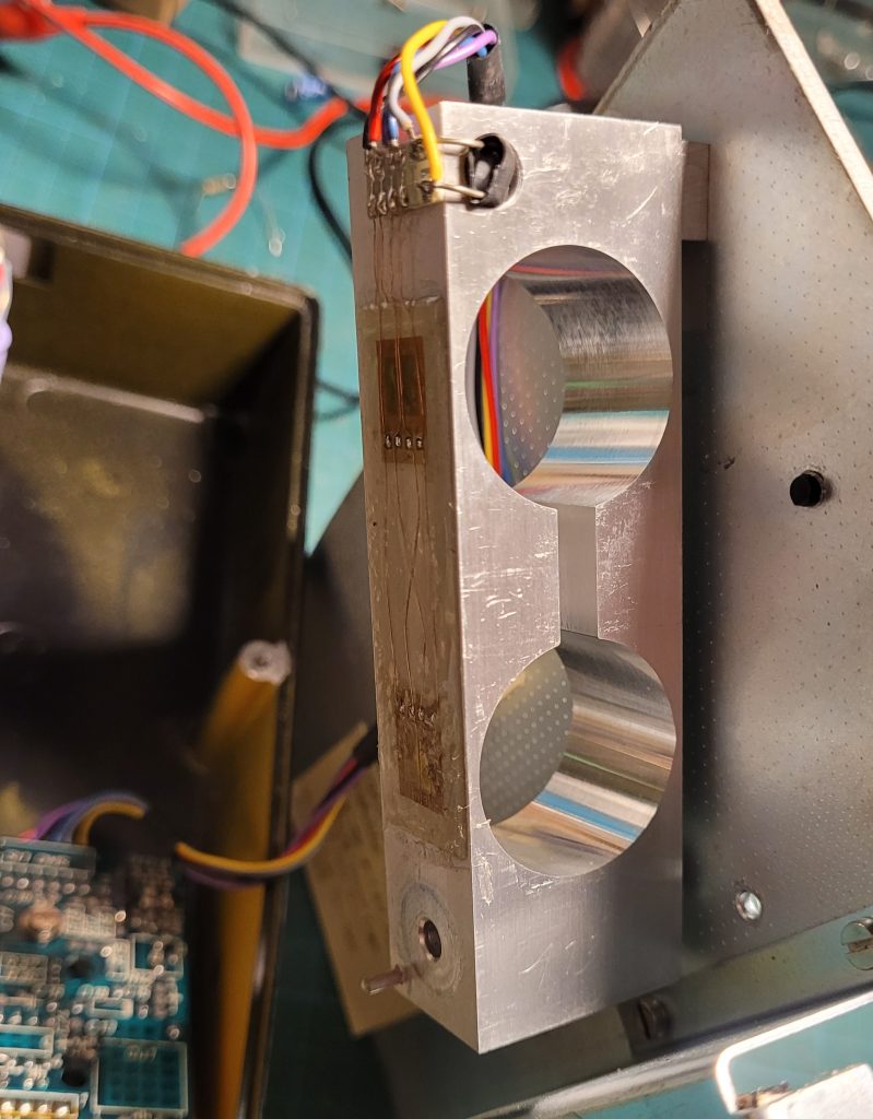 Shows the aluminium bar mount with two large circular holes each with a strain gauge above.